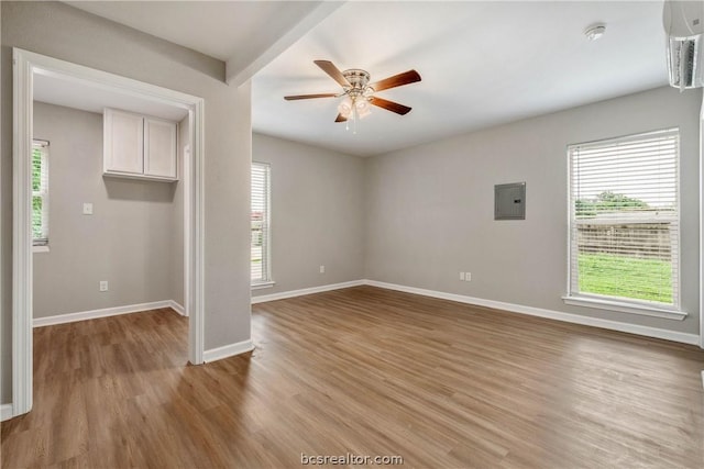 empty room with electric panel, ceiling fan, and light hardwood / wood-style floors