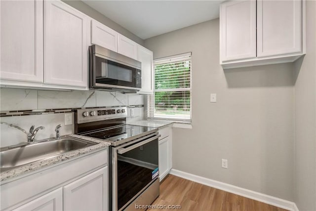 kitchen with backsplash, stainless steel appliances, sink, light hardwood / wood-style flooring, and white cabinetry