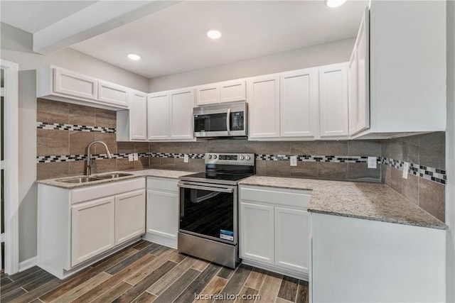 kitchen with sink, dark wood-type flooring, stainless steel appliances, backsplash, and white cabinets