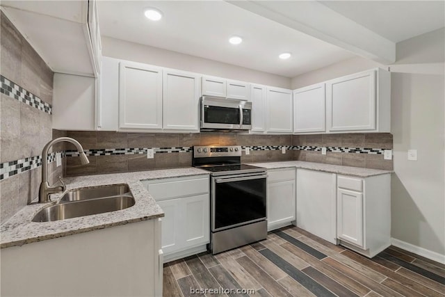 kitchen featuring white cabinetry, sink, dark wood-type flooring, stainless steel appliances, and backsplash