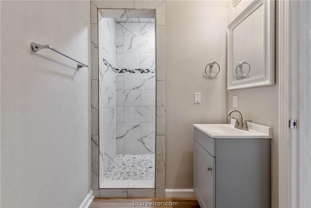 bathroom with vanity, a tile shower, and wood-type flooring