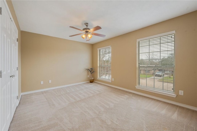 carpeted empty room with ceiling fan and baseboards