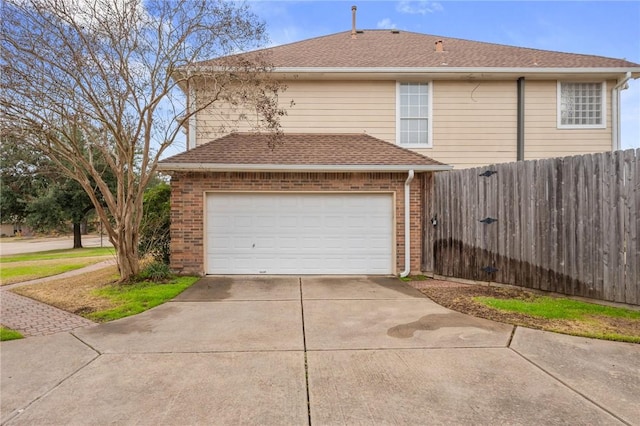 garage with concrete driveway and fence