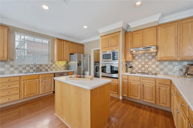 kitchen featuring light wood-style flooring, washer / clothes dryer, stainless steel appliances, under cabinet range hood, and a sink