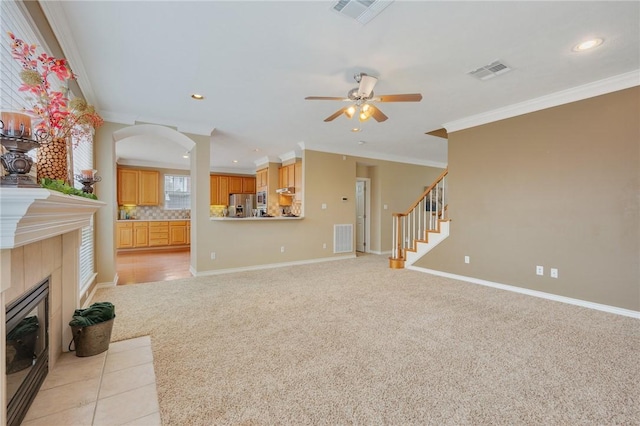 living area featuring light colored carpet, visible vents, a fireplace, and stairway