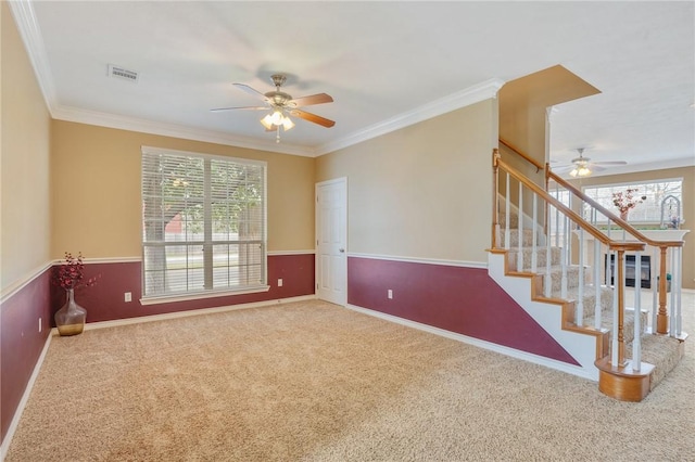 unfurnished room with a ceiling fan, carpet, crown molding, and stairway