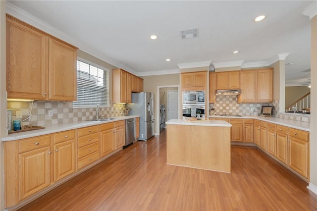 1605 Dominik Dr, College Station, TX 77840 - kitchen with appliances with stainless steel finishes, under cabinet range hood, a sink, light wood finished floors, and tasteful backsplash