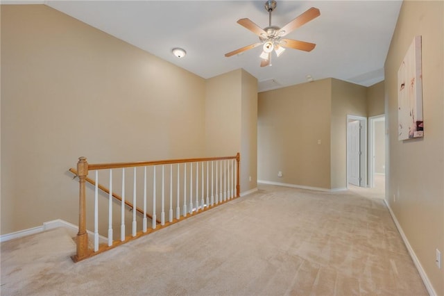 carpeted empty room featuring a ceiling fan and baseboards