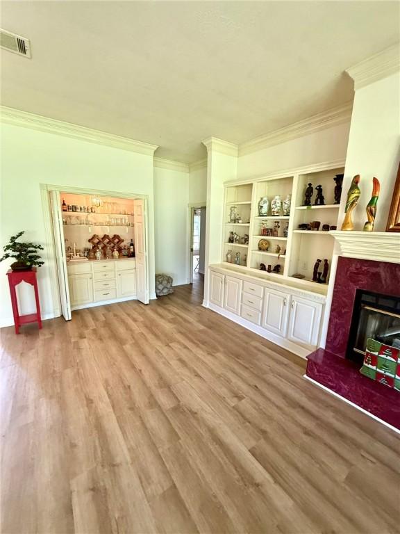 40 Casper Pl, Hilltop Lakes, TX 77871 - unfurnished living room featuring ornamental molding, a fireplace with raised hearth, and wood finished floors