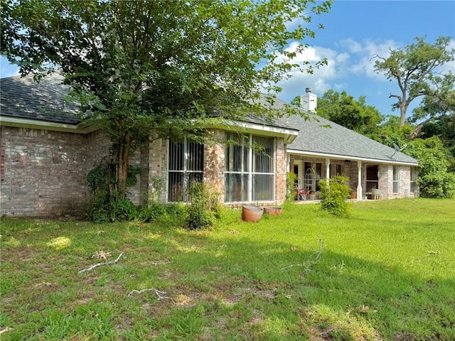 40 Casper Pl, Hilltop Lakes, TX 77871 - rear view of house featuring a yard, brick siding, a chimney, and a shingled roof
