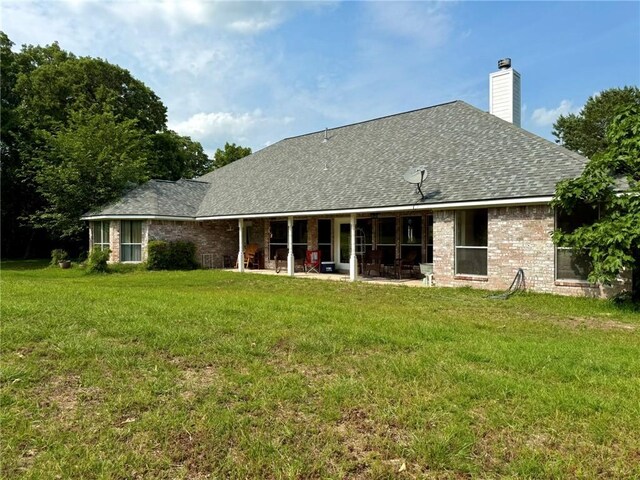 40 Casper Pl, Hilltop Lakes, TX 77871 - rear view of house with a yard, a patio area, a shingled roof, and a chimney