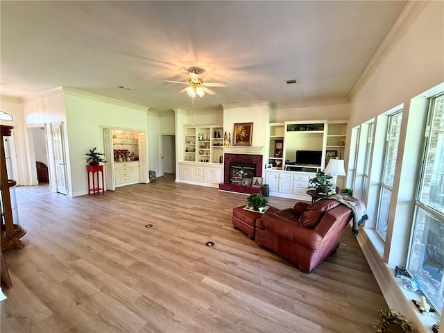 40 Casper Pl, Hilltop Lakes, TX 77871 - living area featuring crown molding, ceiling fan, a fireplace with raised hearth, built in features, and light wood-style floors