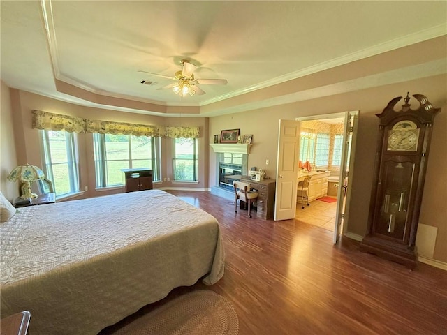 40 Casper Pl, Hilltop Lakes, TX 77871 - bedroom featuring wood finished floors, a glass covered fireplace, baseboards, ornamental molding, and a tray ceiling