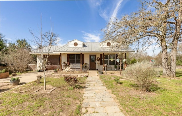 view of front of property with covered porch, driveway, and metal roof