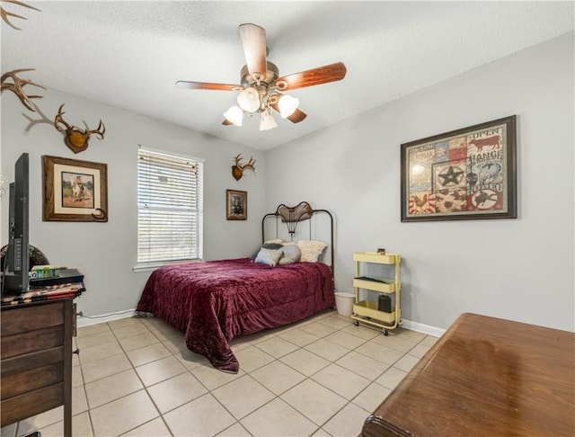 bedroom with light tile patterned floors, baseboards, a textured ceiling, and a ceiling fan