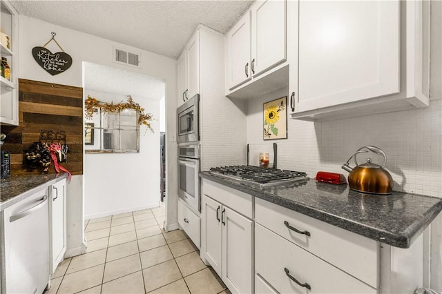 kitchen featuring visible vents, backsplash, appliances with stainless steel finishes, white cabinets, and light tile patterned floors