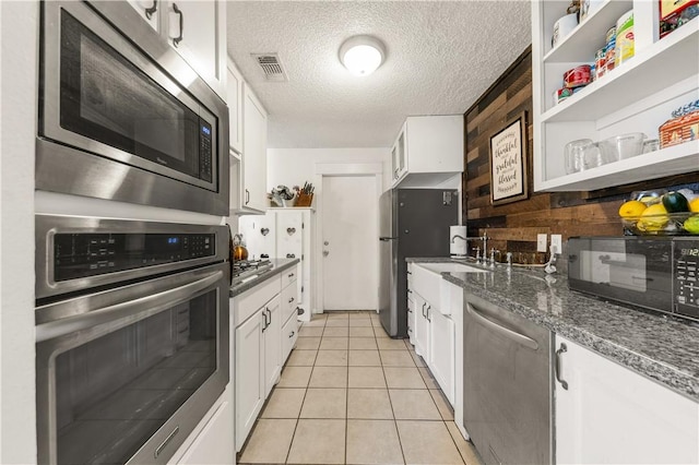 kitchen featuring visible vents, light tile patterned floors, white cabinets, stainless steel appliances, and open shelves