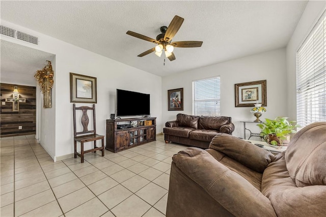 living room with visible vents, a textured ceiling, light tile patterned flooring, and a ceiling fan