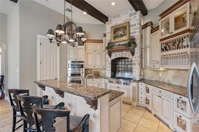 kitchen with hanging light fixtures, a kitchen breakfast bar, a notable chandelier, dark stone countertops, and appliances with stainless steel finishes