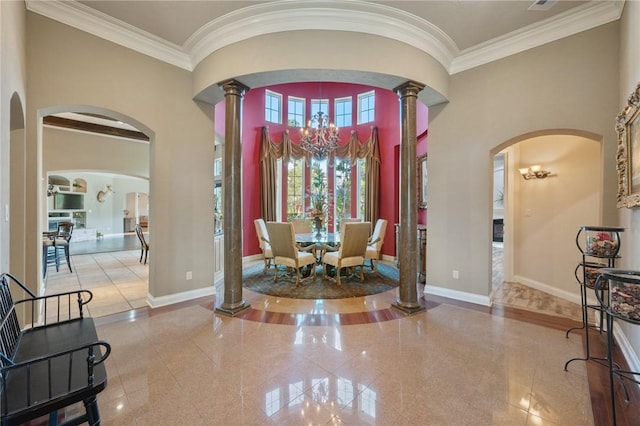 foyer featuring a notable chandelier, ornate columns, crown molding, and a high ceiling