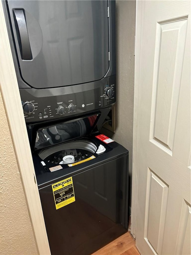 laundry area with wood-type flooring and stacked washer and clothes dryer