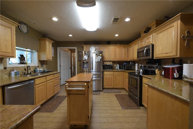 7523 State Highway 21 W, Caldwell, TX 77836 - kitchen with appliances with stainless steel finishes, a sink, backsplash, light wood-type flooring, and light brown cabinetry