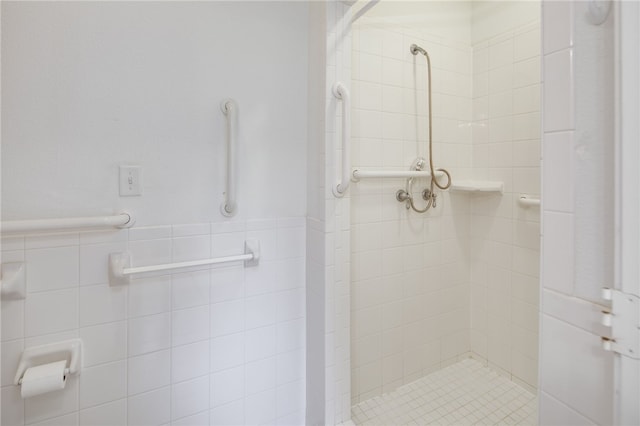 full bathroom featuring wainscoting, a shower stall, and tile walls