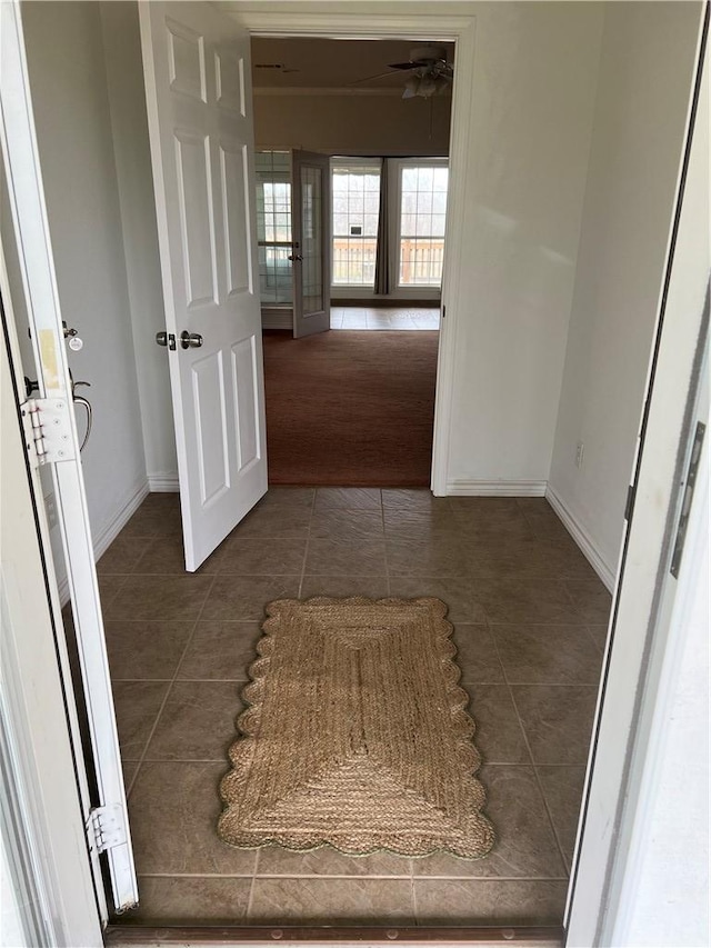 corridor featuring dark tile patterned floors and baseboards