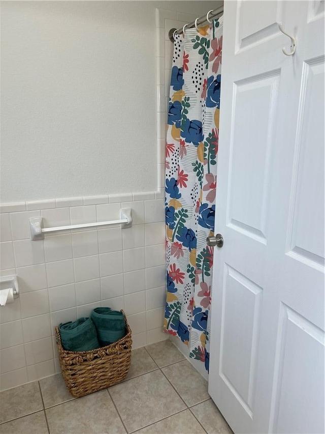 bathroom with tile patterned flooring, a wainscoted wall, tile walls, and curtained shower