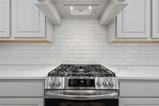 kitchen featuring stainless steel range, tasteful backsplash, white cabinets, and light stone counters