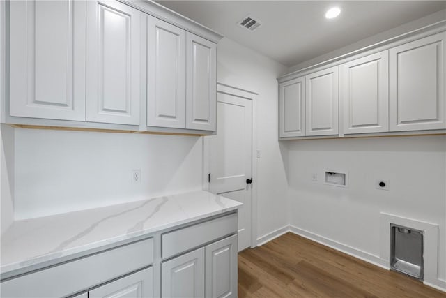 laundry area featuring electric dryer hookup, washer hookup, cabinets, and hardwood / wood-style flooring