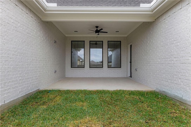 doorway to property with ceiling fan, a patio area, and a lawn