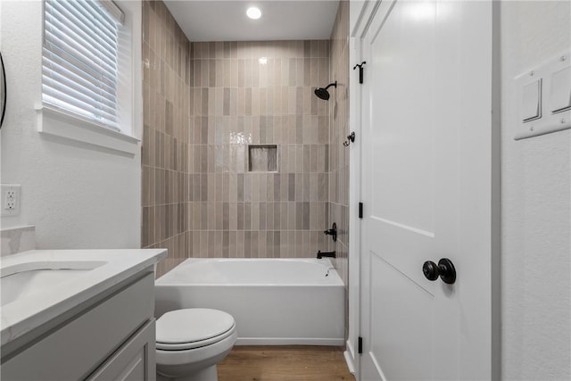 full bathroom with vanity, wood-type flooring, tiled shower / bath combo, and toilet