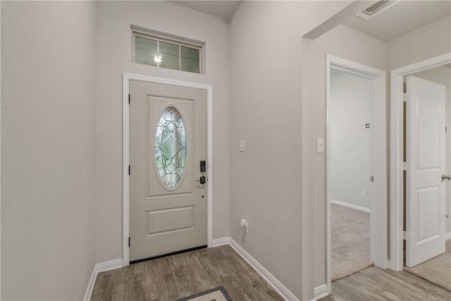 foyer featuring visible vents, baseboards, and wood finished floors