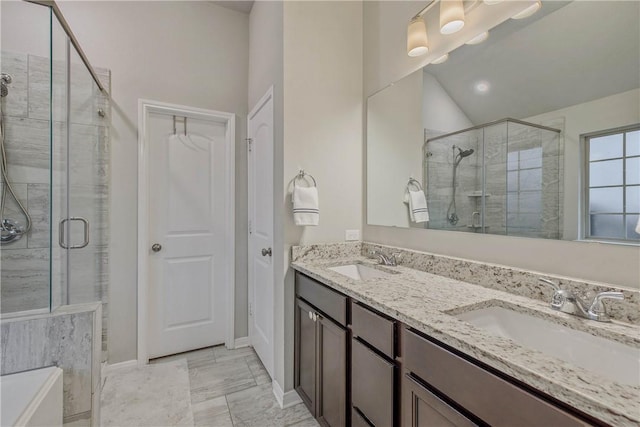 bathroom featuring baseboards, double vanity, a sink, and a shower stall