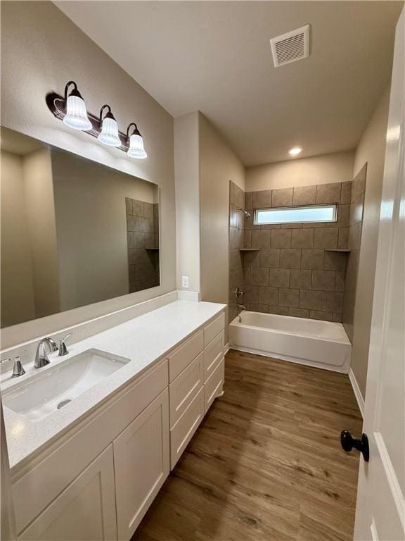 bathroom with tiled shower / bath, wood-type flooring, and vanity