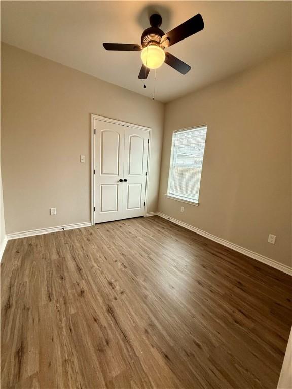 unfurnished bedroom with hardwood / wood-style flooring, a closet, and ceiling fan