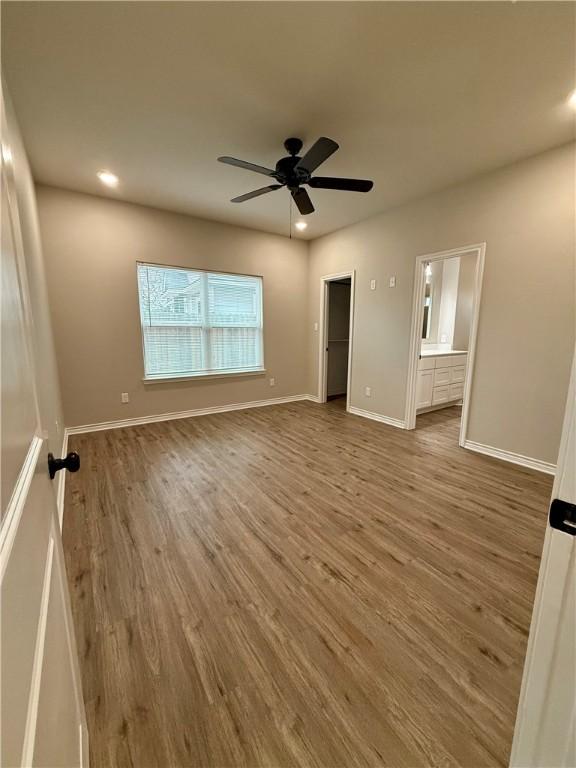 unfurnished bedroom with hardwood / wood-style floors, ceiling fan, and ensuite bathroom