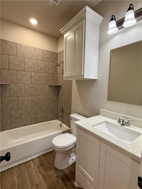 full bathroom featuring wood-type flooring, toilet, vanity, and tiled shower / bath