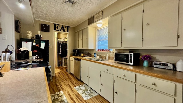 kitchen with a textured ceiling, stainless steel appliances, crown molding, sink, and light hardwood / wood-style floors