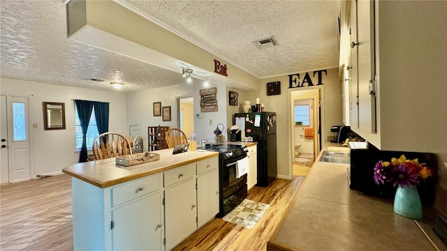 kitchen featuring black appliances, light hardwood / wood-style floors, sink, and a textured ceiling