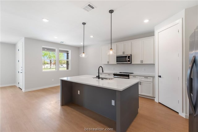 1405 Conner St, Bryan, TX 77808 - kitchen with white cabinets, an island with sink, decorative light fixtures, and appliances with stainless steel finishes