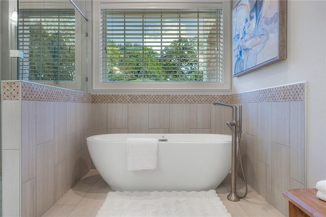 bathroom with tile patterned flooring, tile walls, and plus walk in shower