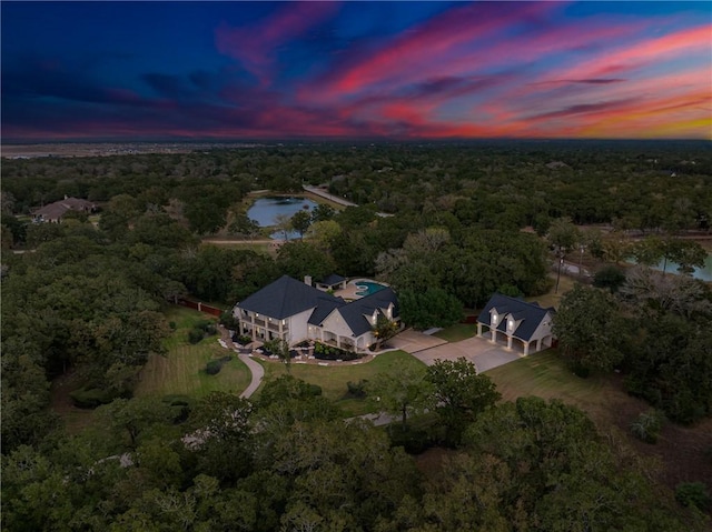 aerial view at dusk with a water view and a forest view