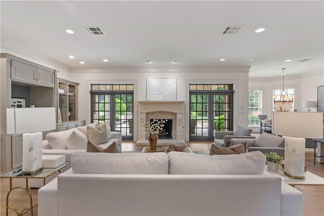 living area featuring ornamental molding, a wealth of natural light, visible vents, and wood finished floors