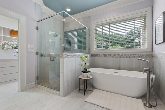bathroom featuring a shower stall, a freestanding bath, ornamental molding, tile patterned flooring, and wainscoting