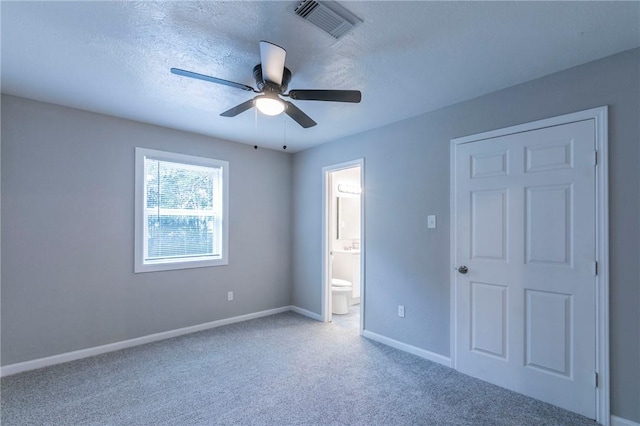 unfurnished bedroom featuring carpet flooring, a textured ceiling, connected bathroom, and ceiling fan