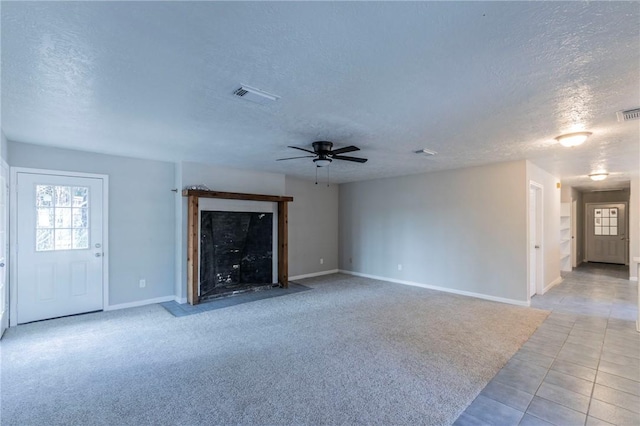 unfurnished living room with ceiling fan, light tile patterned floors, and a textured ceiling