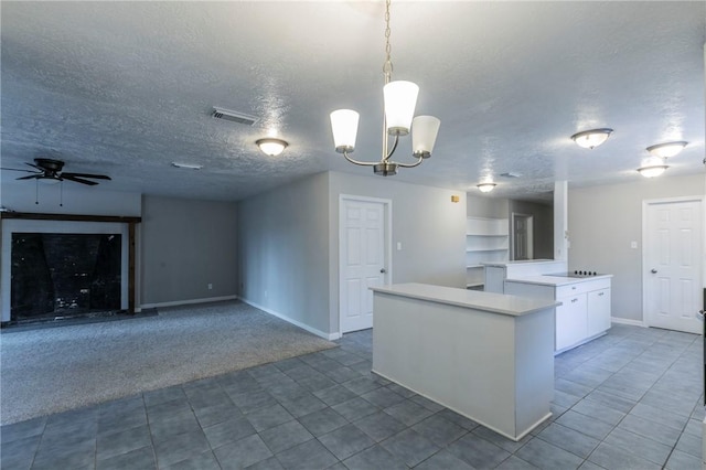 kitchen featuring carpet flooring, a textured ceiling, ceiling fan with notable chandelier, pendant lighting, and white cabinets