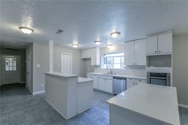 kitchen featuring white cabinets, appliances with stainless steel finishes, a textured ceiling, and a kitchen island